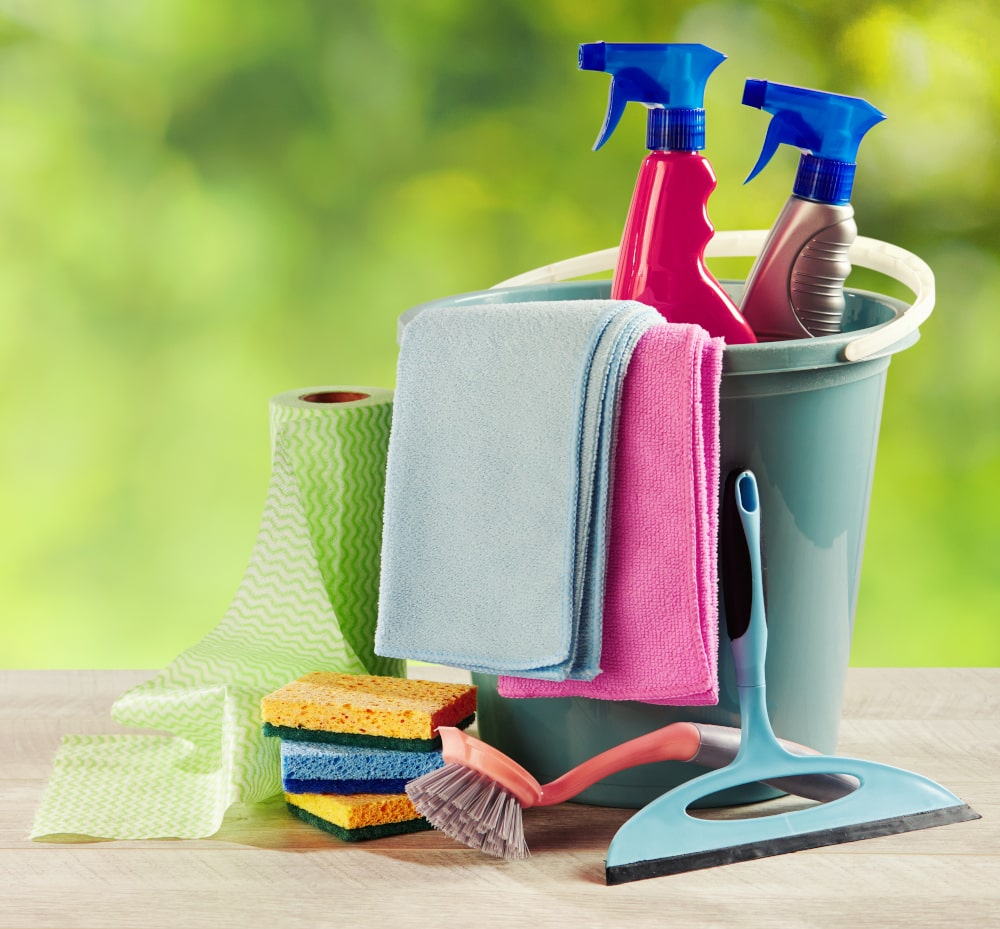 Spring cleaning bucket, scrubbing brush, sponges, towels, spray bottles outdoors